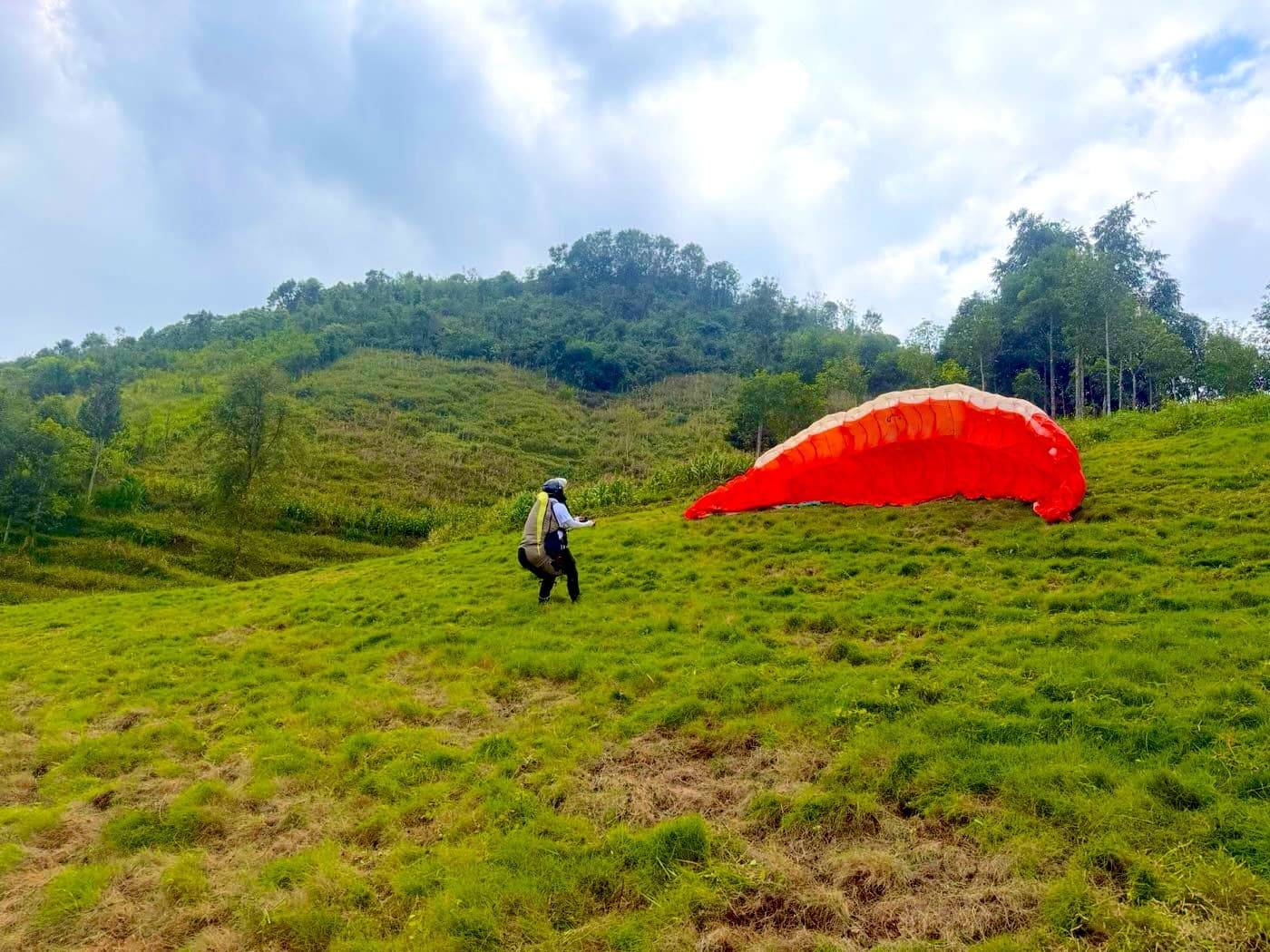 A pilot raising a red wing on the grassy Quản Bạ take-off