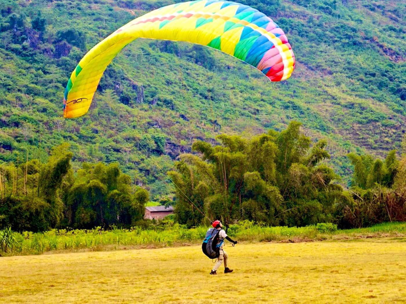 A pilot kiting a rainbow wing on the Quản Bạ landing field