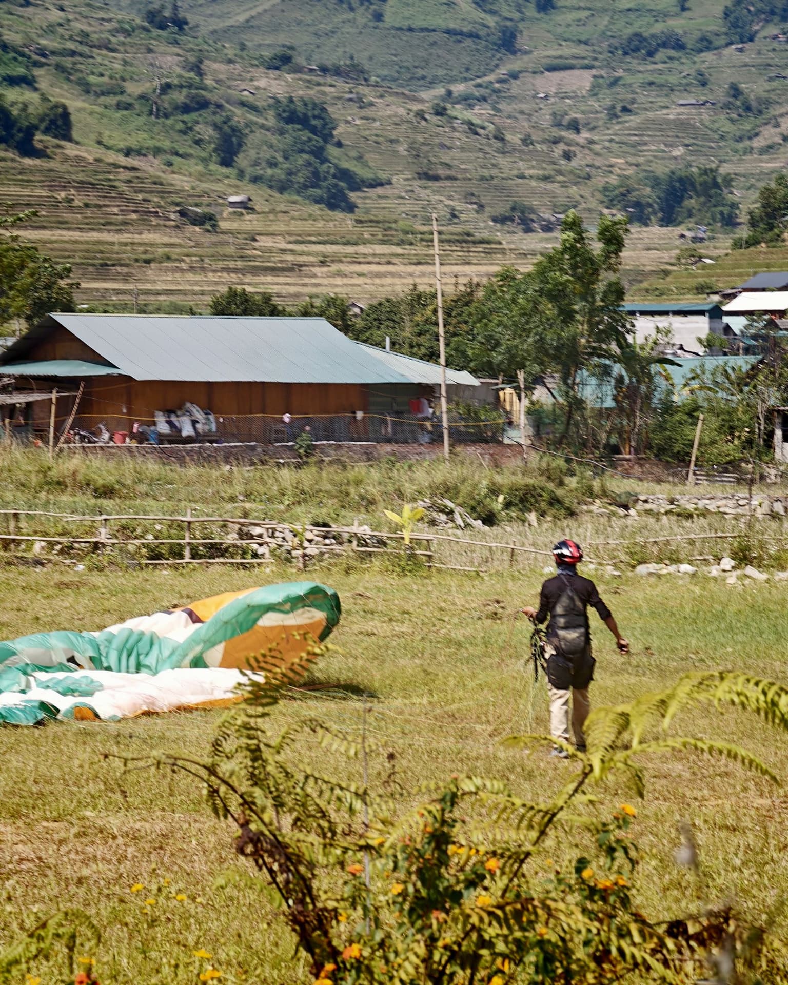 The wing is down; the pilot keeps the lines tight and walks towards it to gather it.