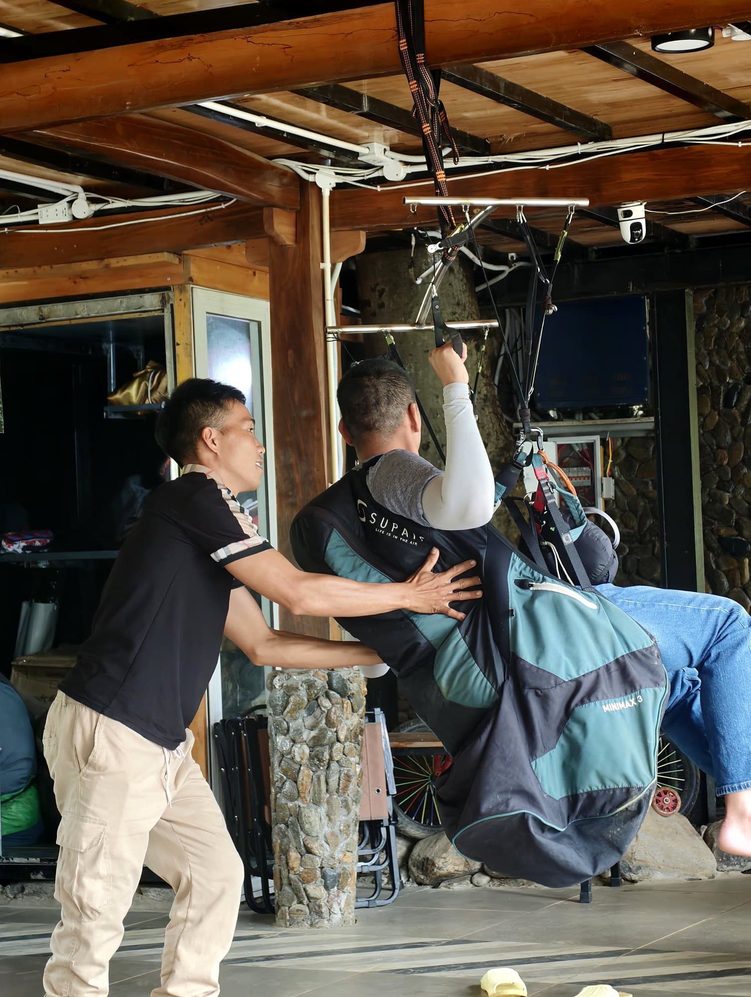 The instructor pushes and turns the harness on the simulator so the student practises reacting while unsettled.
