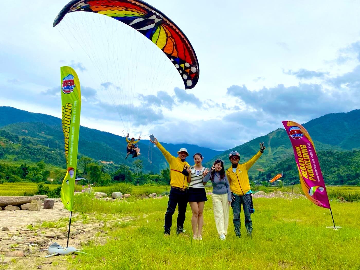 Guests and pilots celebrating on the Lim Thai landing field as a butterfly wing comes in behind