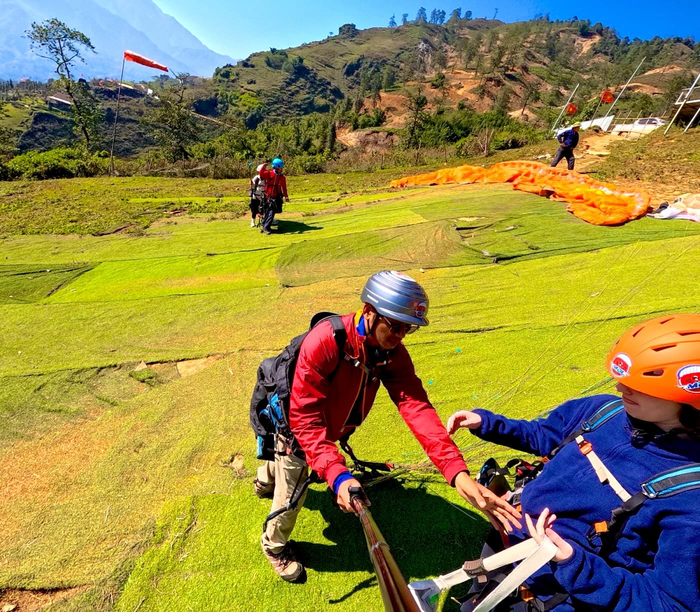 Bãi cất cánh Sa Pa: thảm cỏ xanh, phi công móc dây cho khách, cánh dù trải sẵn phía sau