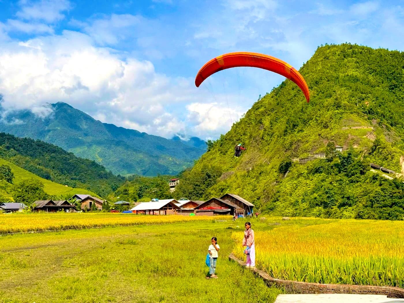 Dù lượn trên bãi hạ cánh, núi phía sau