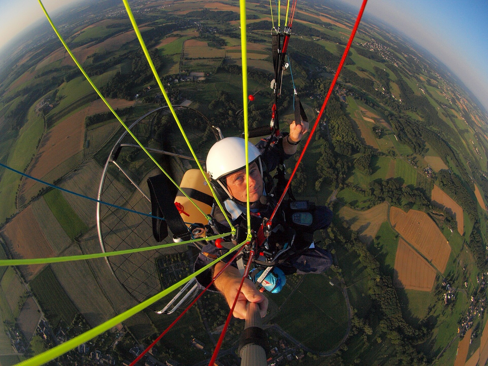 Phi công paramotor cất cánh bằng chân đang bay: tay phải cầm tay ga, tay trái giữ tay phanh